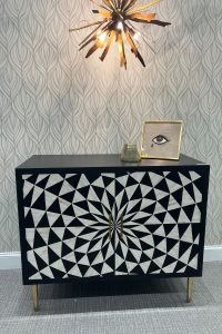 black and white accent chest with a triangle pattern in a circular form wth gold legs and hardware