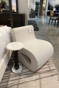 a really cool cureved/wavy white boucle chair with a sculpturally stacked base accent table
