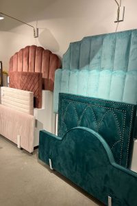 multiple upholstered headboards in rich emerald greens, teals, and rust colors